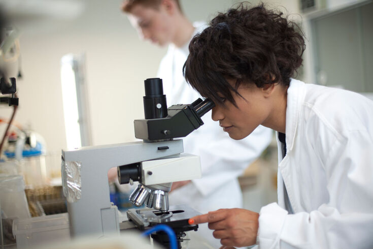 Studentin der Chemie vor einem Mikroskop.