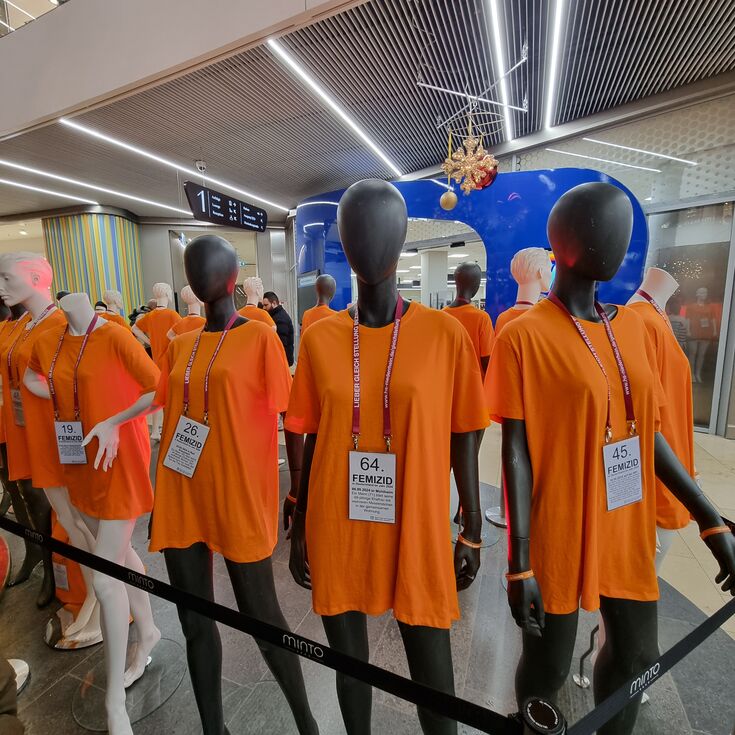 Aufnahme von vier Schaufensterpuppen mit orangenen Shirts und Halsband, auf dem ihre Todesursache beschrieben wird.