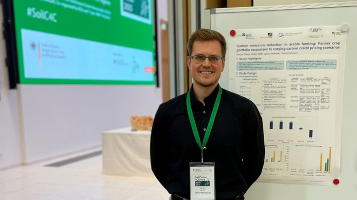 Florian Grebe vor einem Plakat, auf der SoilCarbon4Climate-Konferenz.